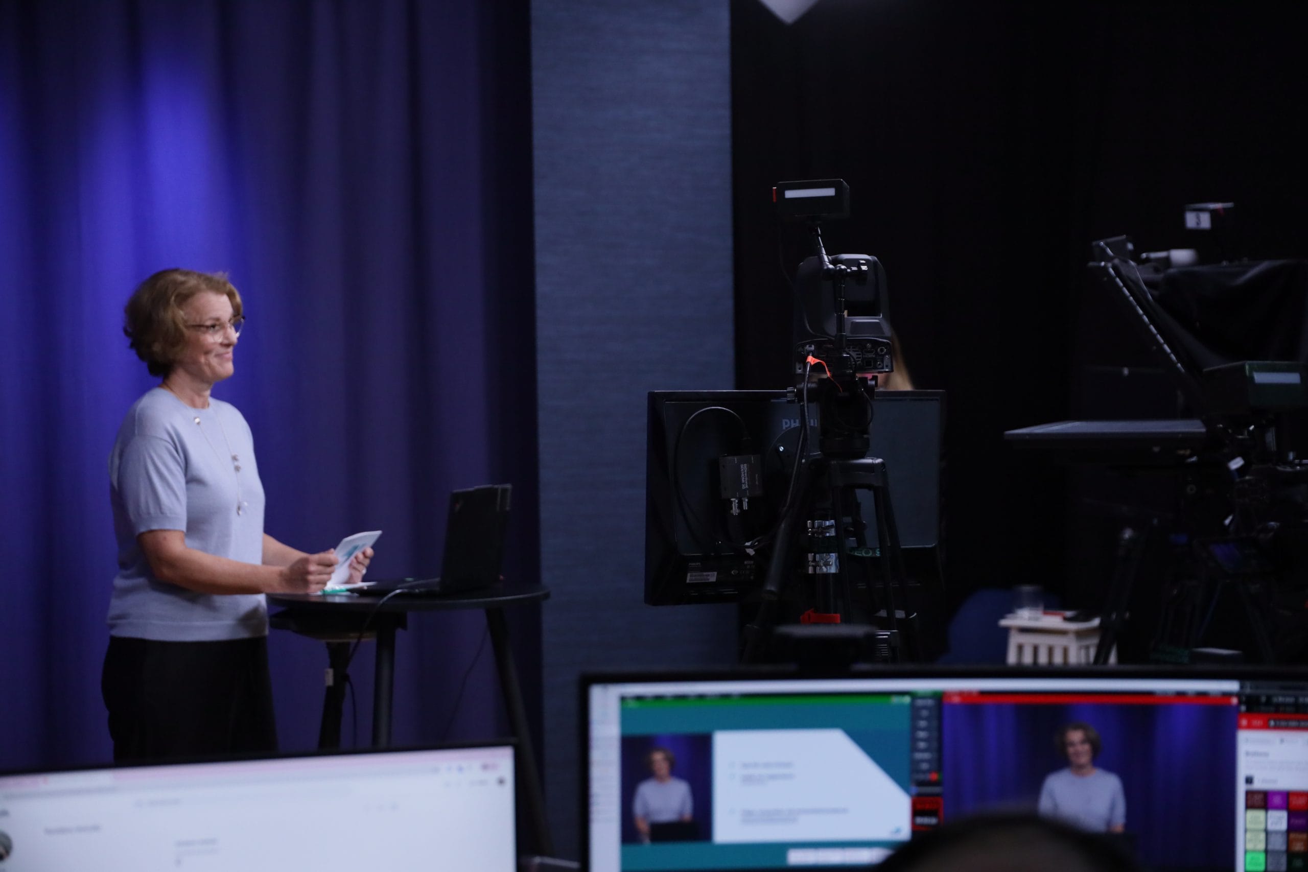 Studion med mörk bakgrund och mörkblå ljussättning. Två män står bakom ett ståbord i trä.